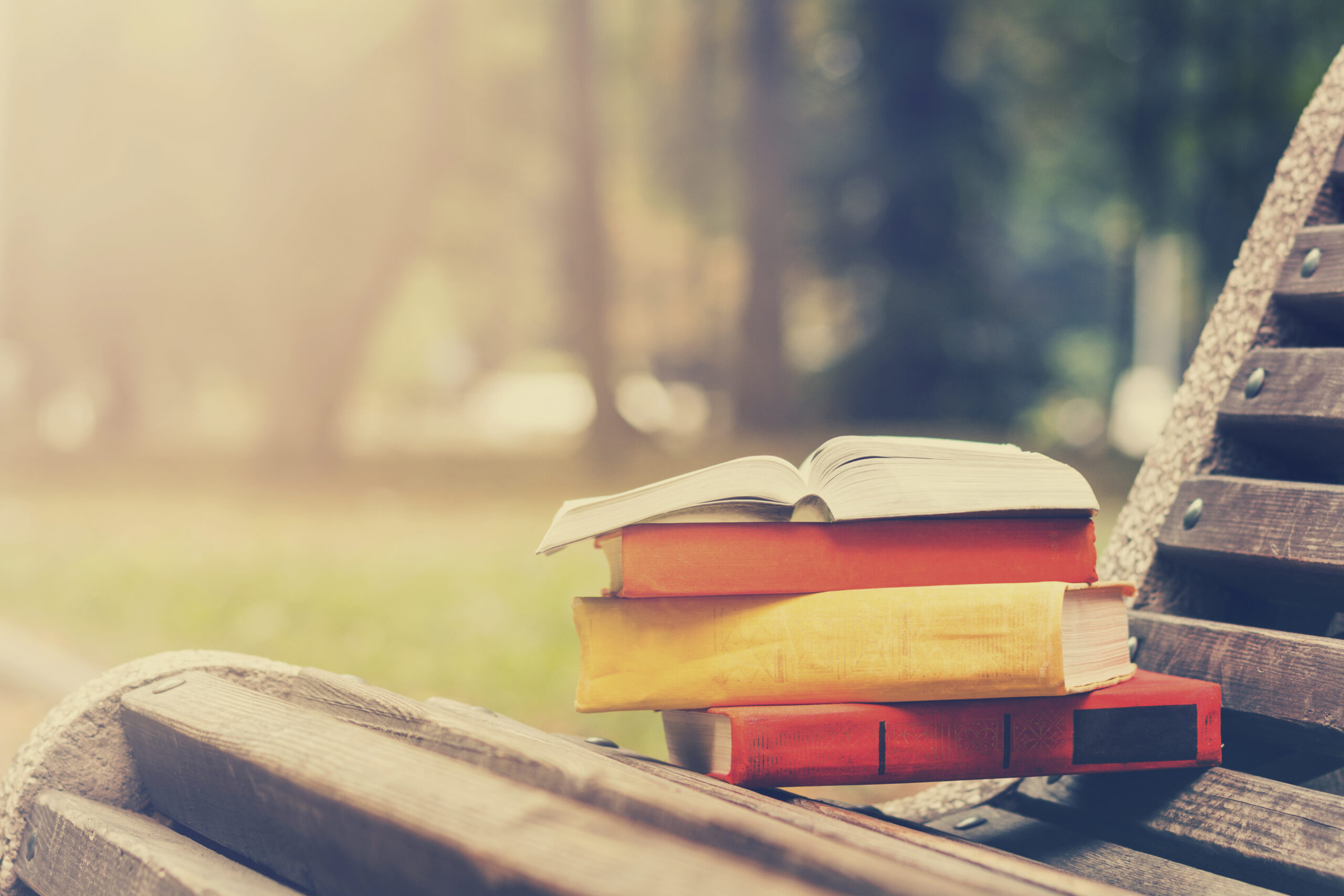 Stack of hardback books and Open book lying on bench College