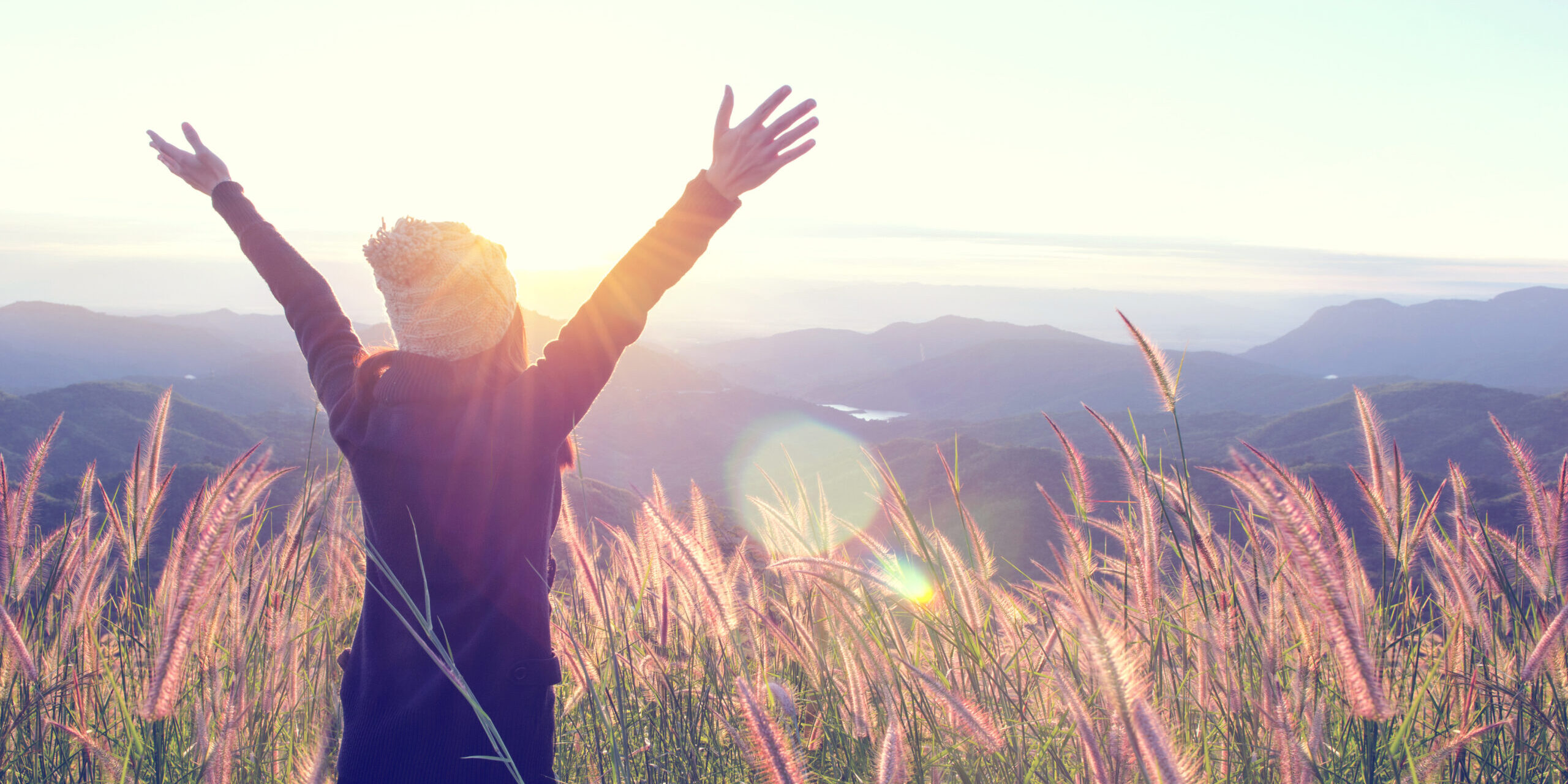 Happy Woman Enjoying Nature on meadow on top of mountain with sunrise. Outdoor. Freedom concept.