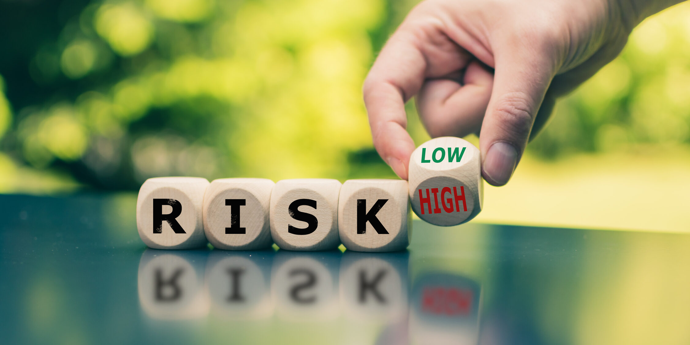 Symbol for reducing a risk. Cubes form the word “RISK” while a hand turns a cube and changes the word “high” to low” (or vice versa).